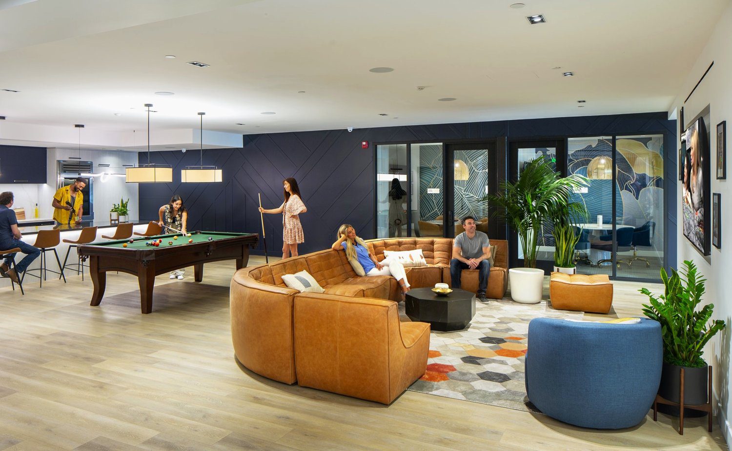 A group of people are sitting in an office with enhanced amenities like a pool table.