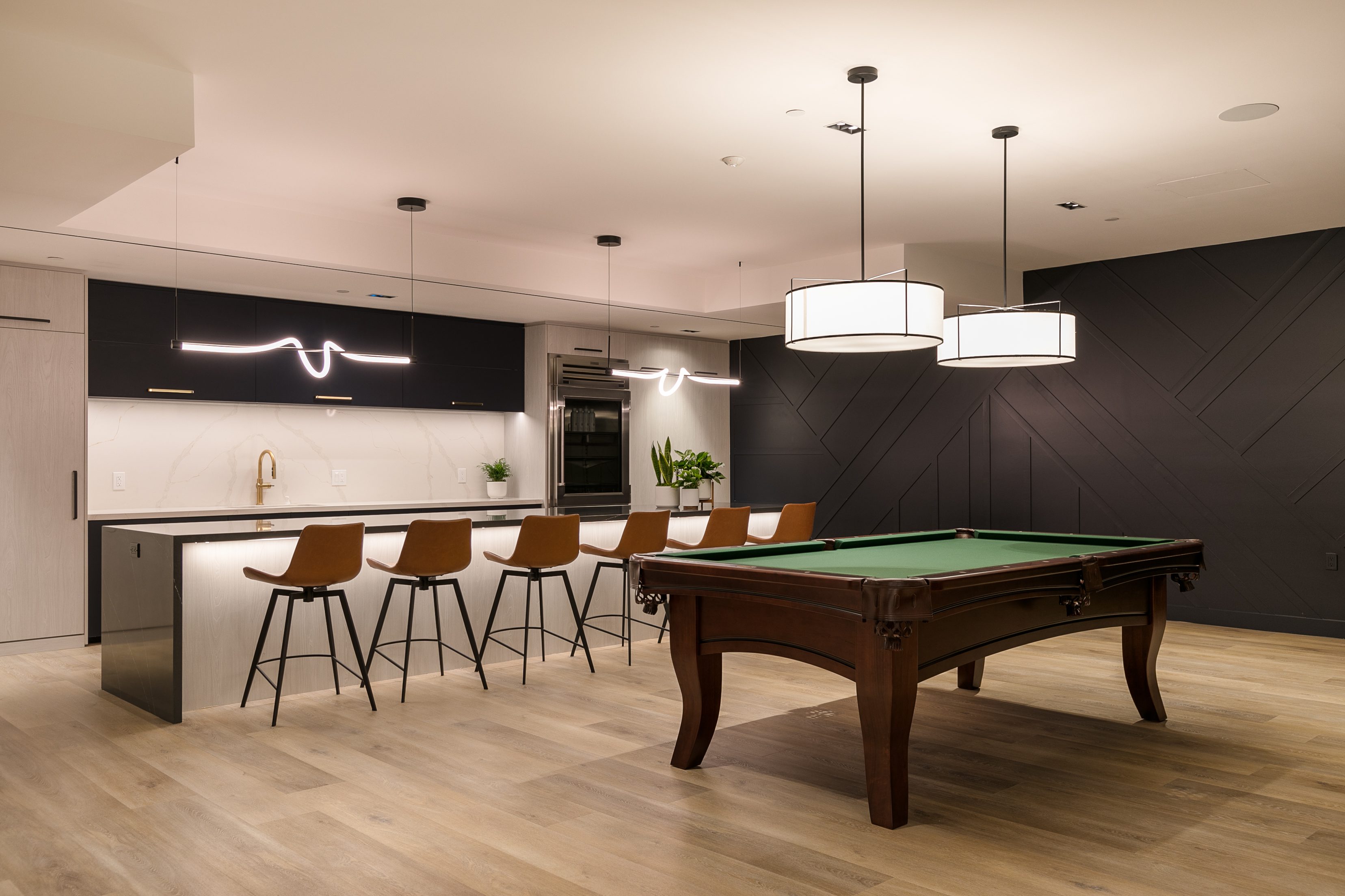 A multifamily apartment featuring The Rinrose game room equipped with a pool table and bar stools.