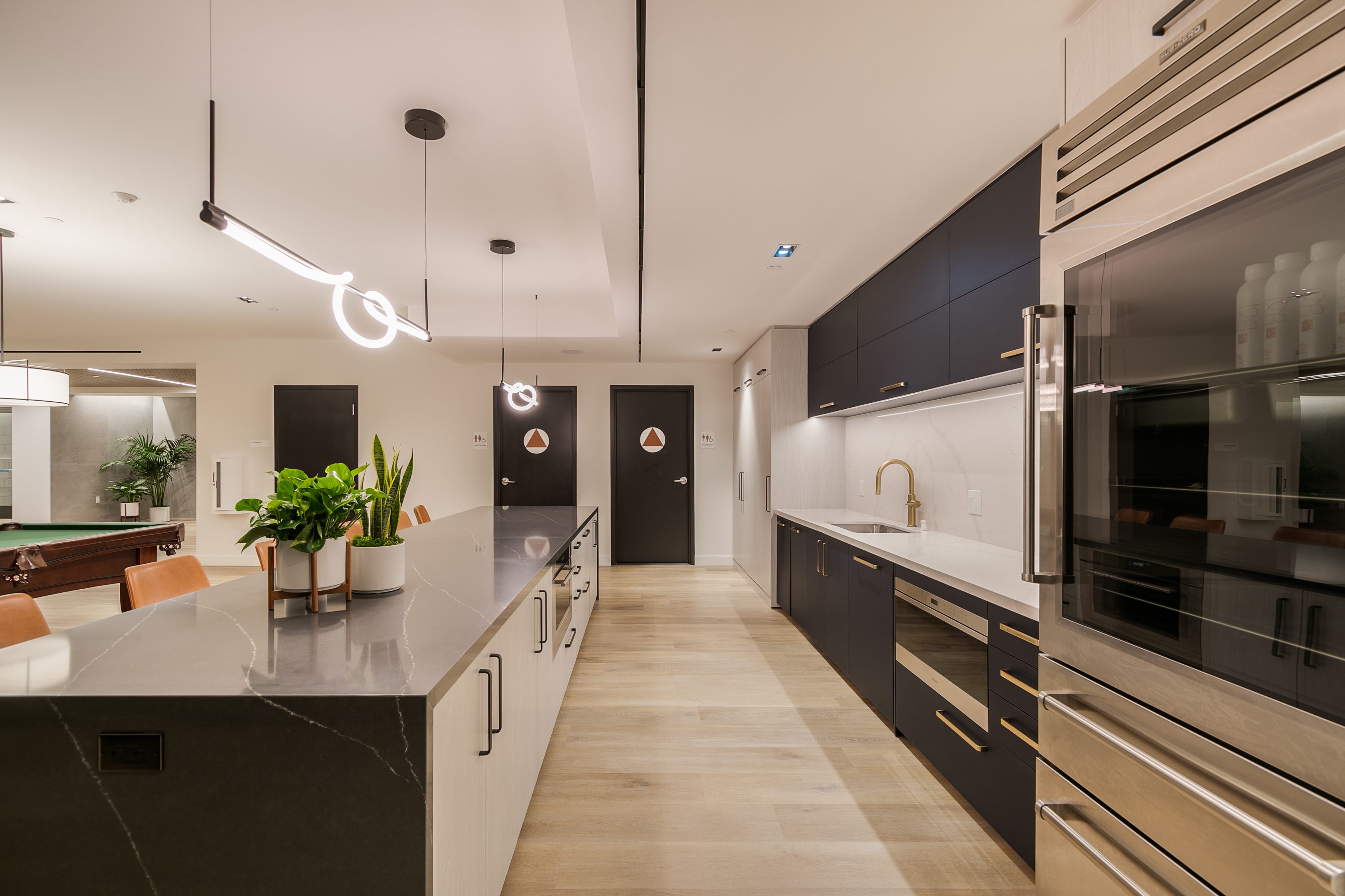A multifamily kitchen in Pasadena designed with a pool table and a refrigerator at The Rinrose.