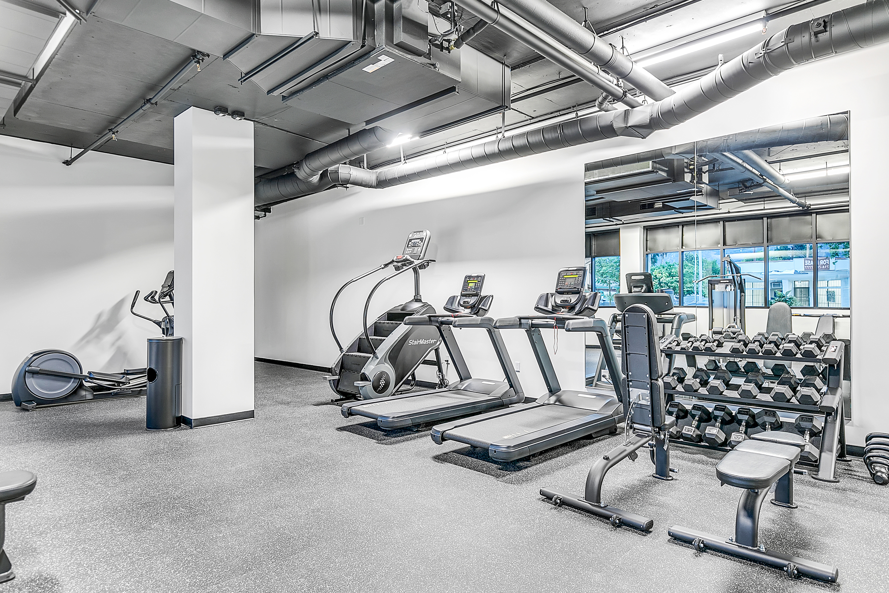 The Rinrose in Pasadena offers a multifamily gym room with exercise equipment and mirrors.