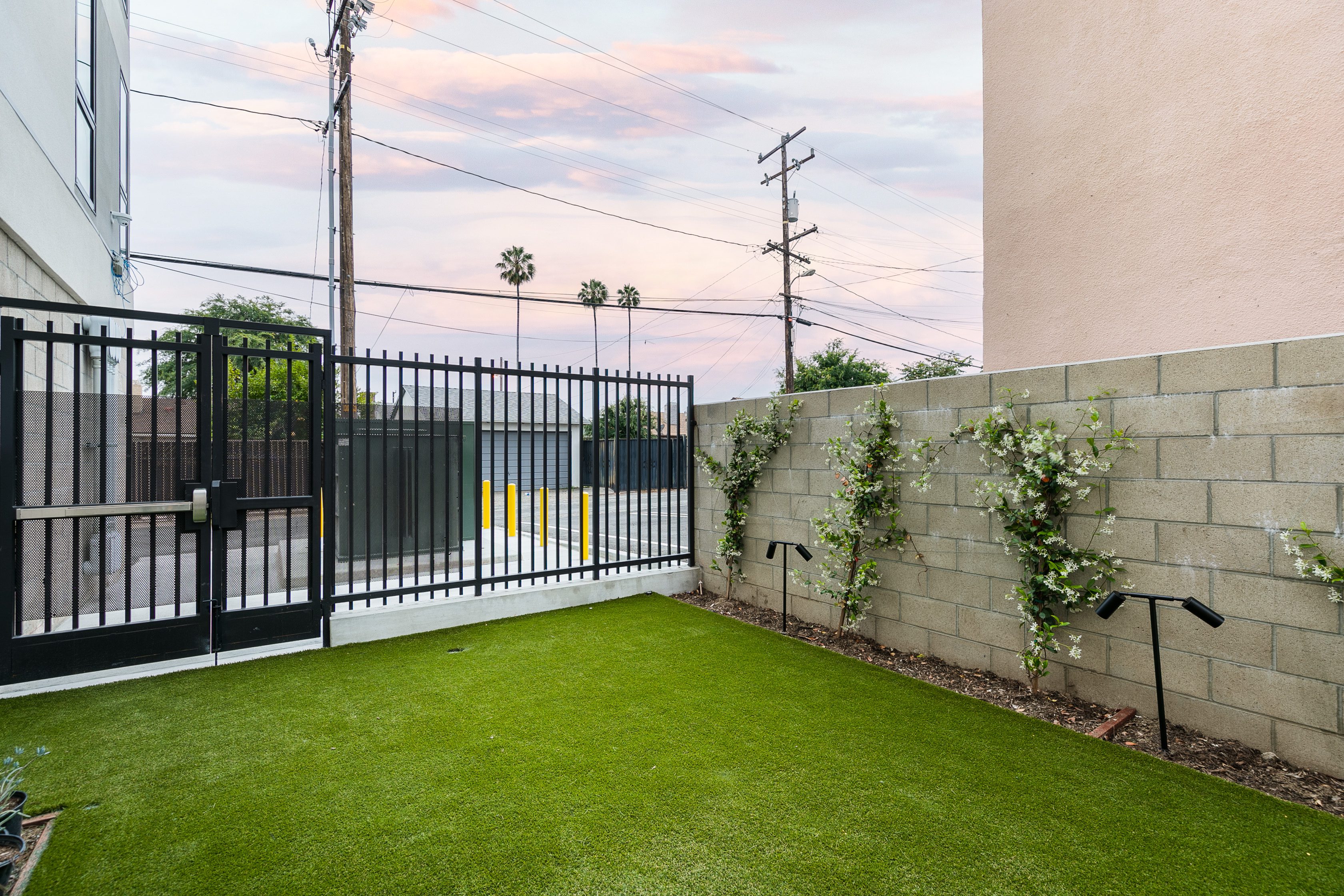 A multifamily apartment in Pasadena with a backyard featuring artificial grass and a fence.