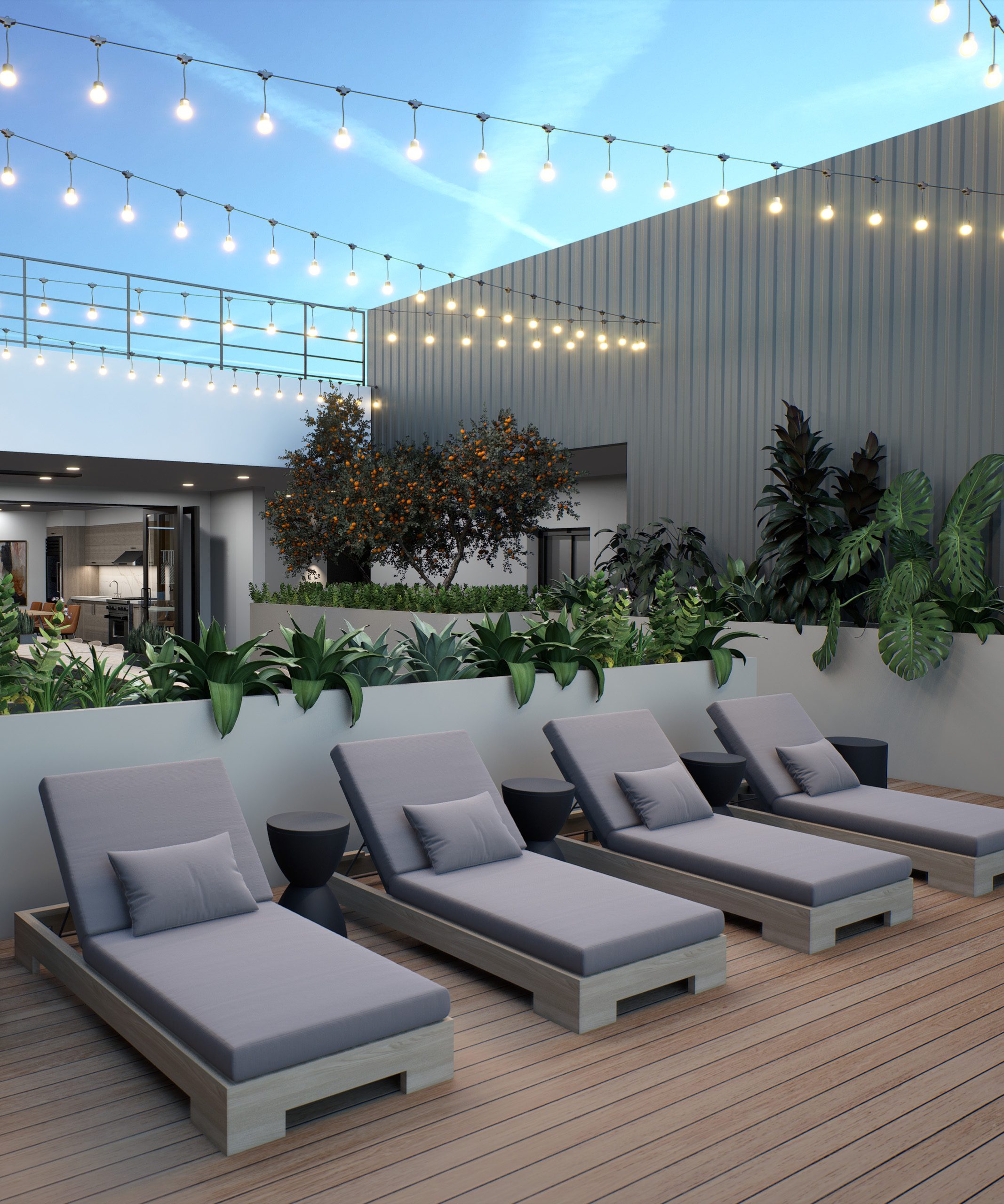 Gray lounge chairs on outdoor patio with greenery and string lights above