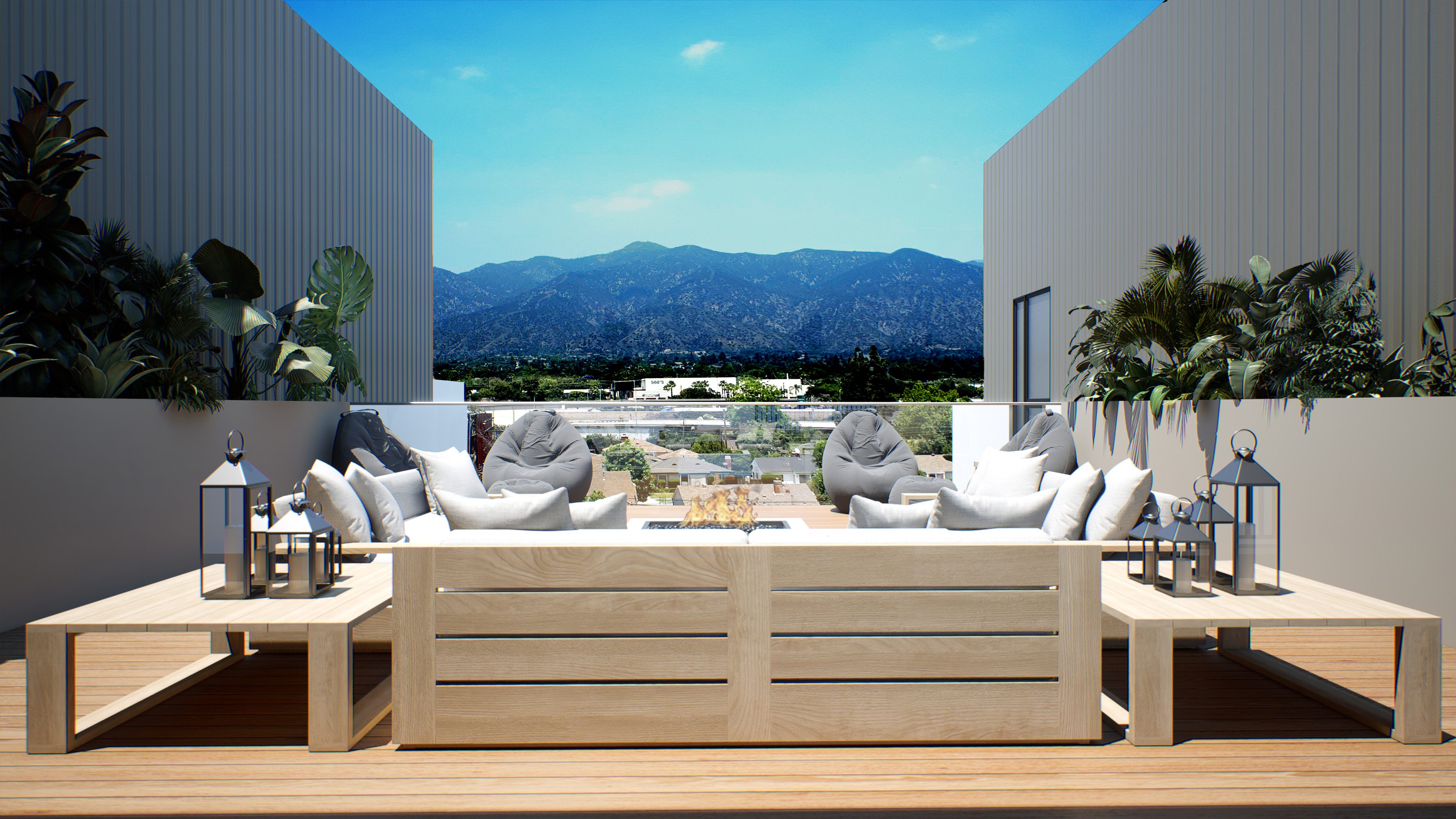 Outdoor patio with cream couches and gray bean bag seating with greenery and a view of Pasadena hills against blue sky
