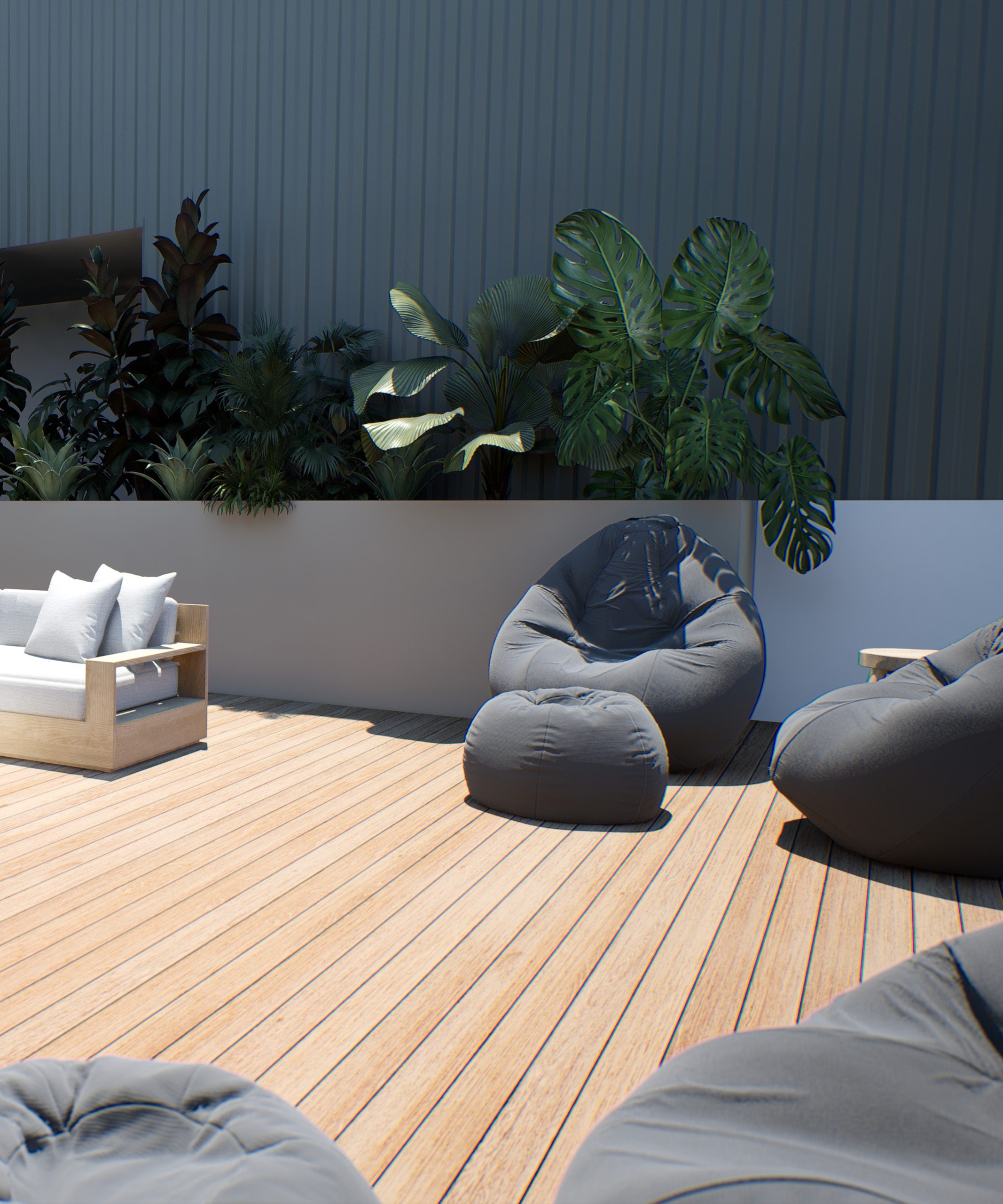 Close up of dark gray bean bag chairs on outdoor patio with greenery behind and cream wooden couch in the corner