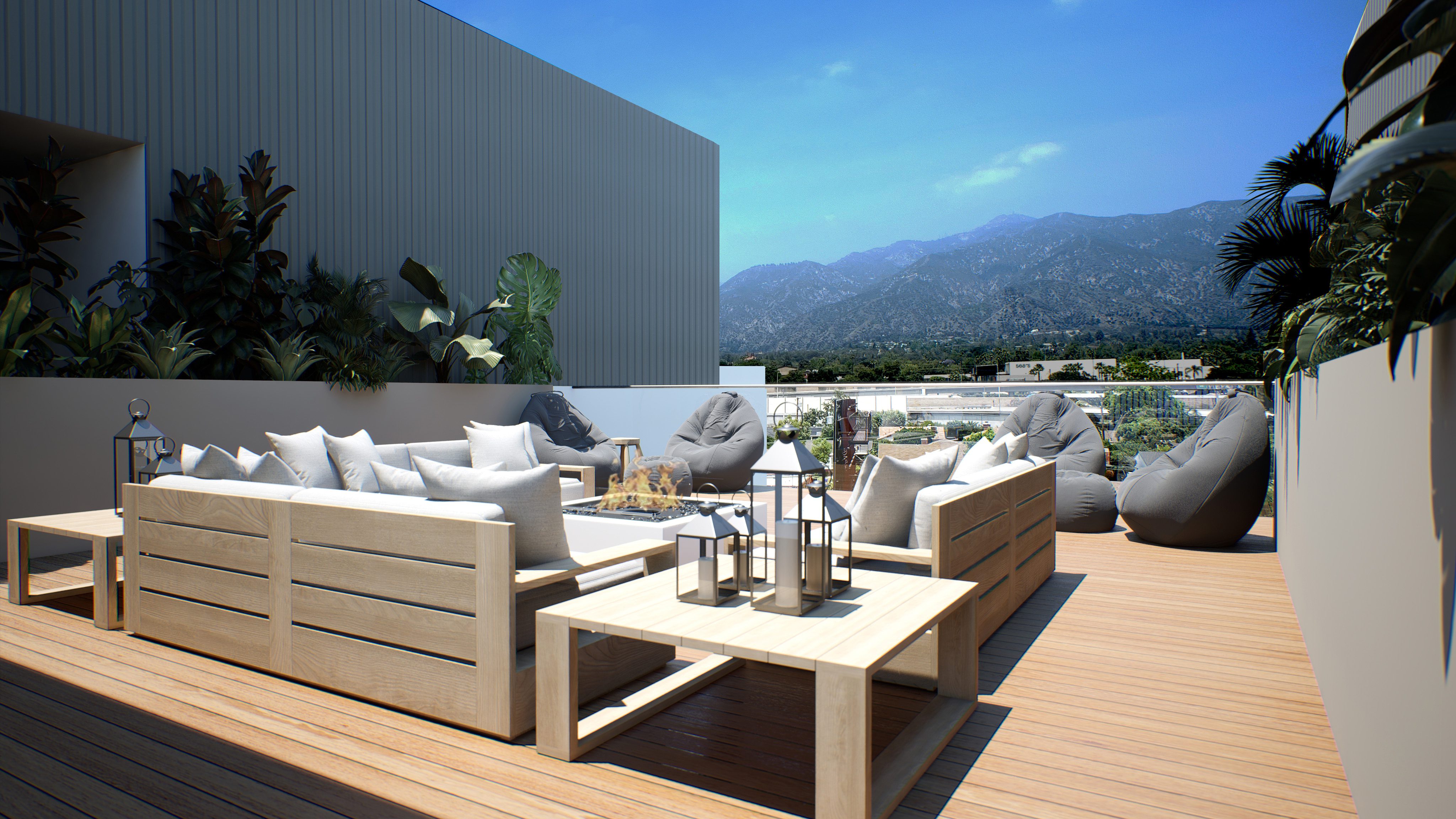 Patio with cream wooden couches, fire pit, dark gray bean bag seating, greenery and view of Pasadena hills