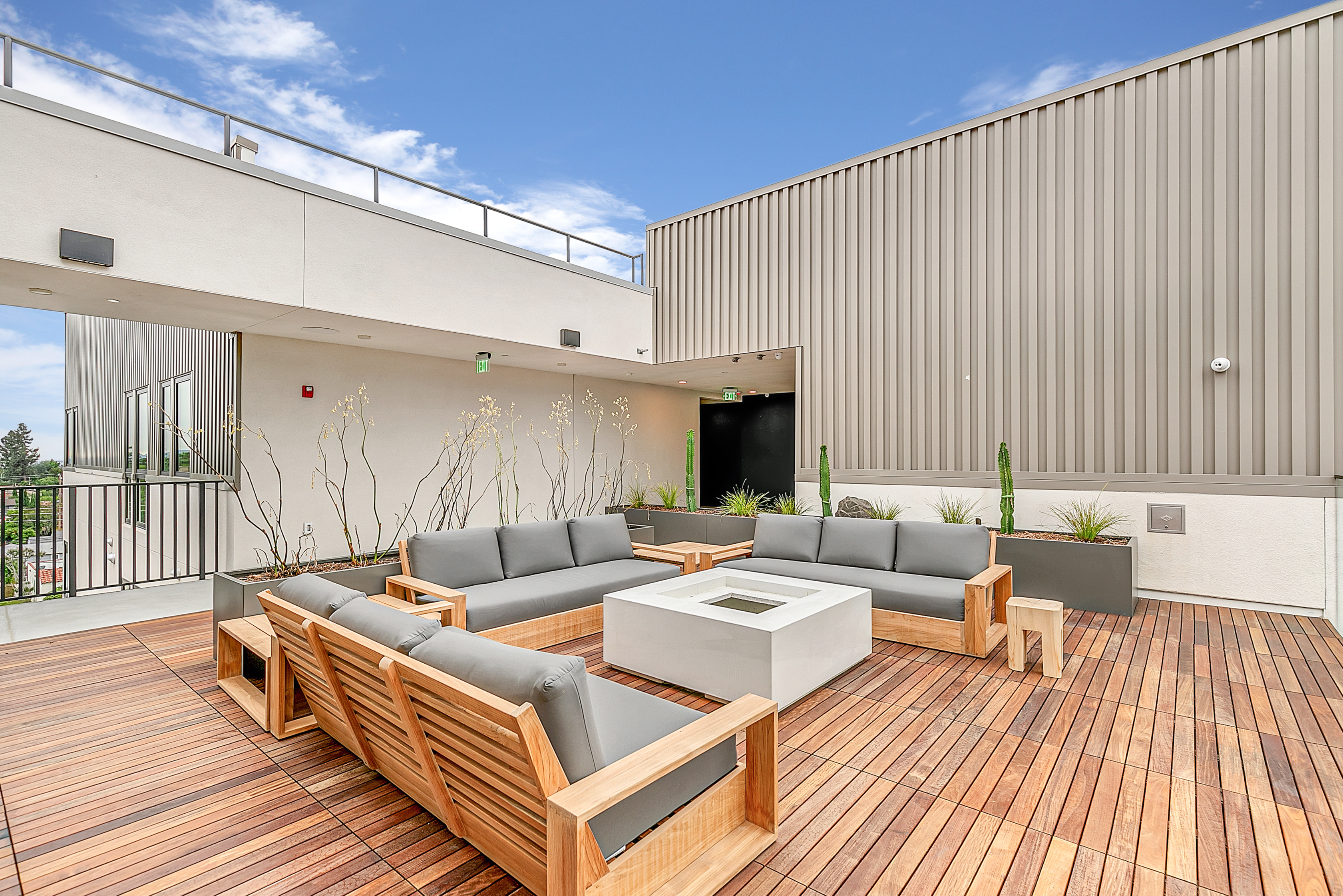 An apartment deck with couches and a fire pit at The Rinrose in Pasadena.