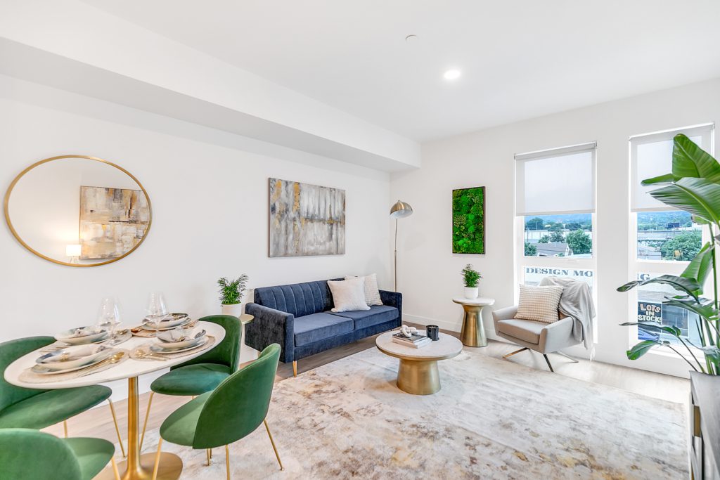 A living room with green chairs and a dining table in a multifamily apartment at The Rinrose.