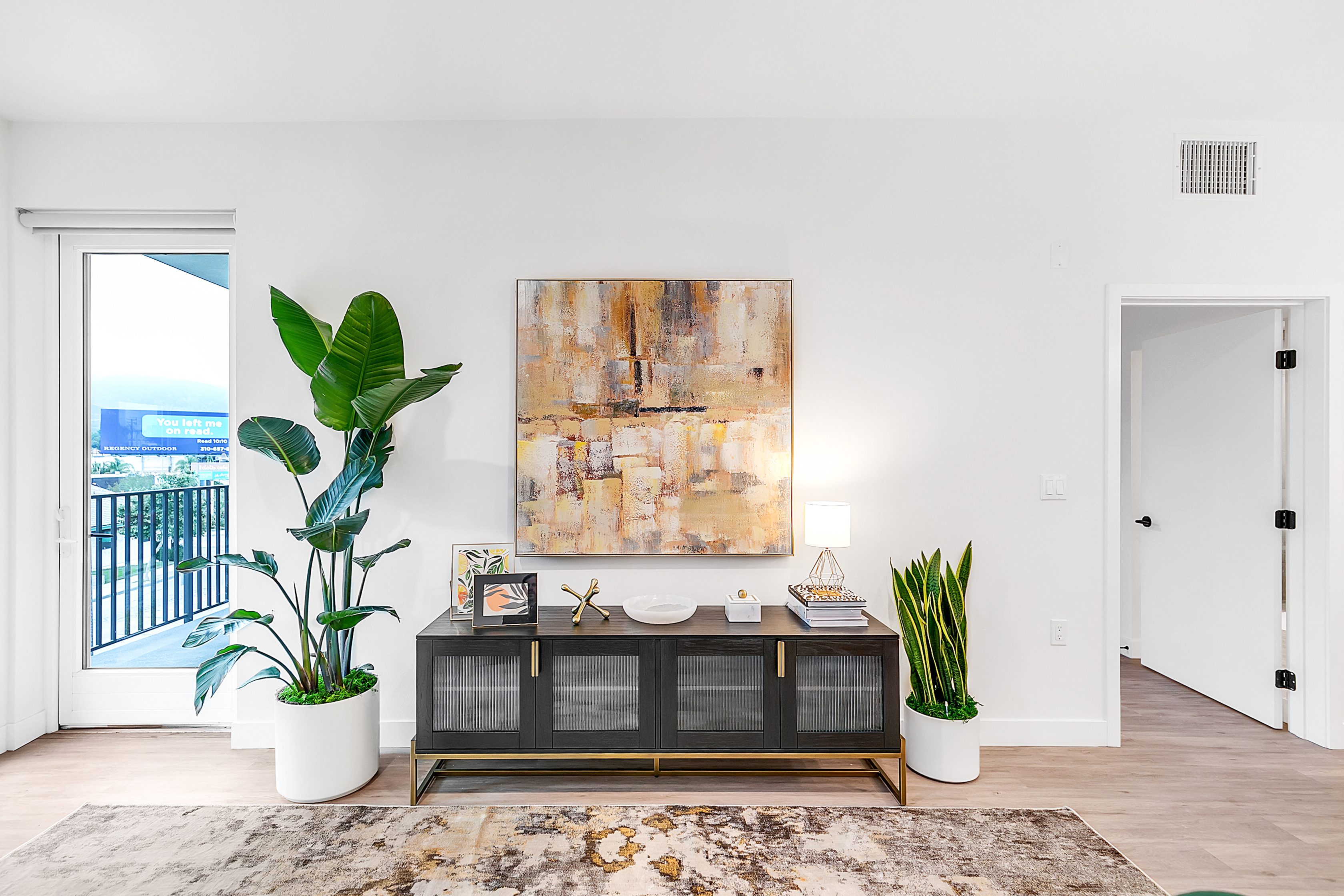 A multifamily living room in The Rinrose, Pasadena with white walls and a plant on the floor.