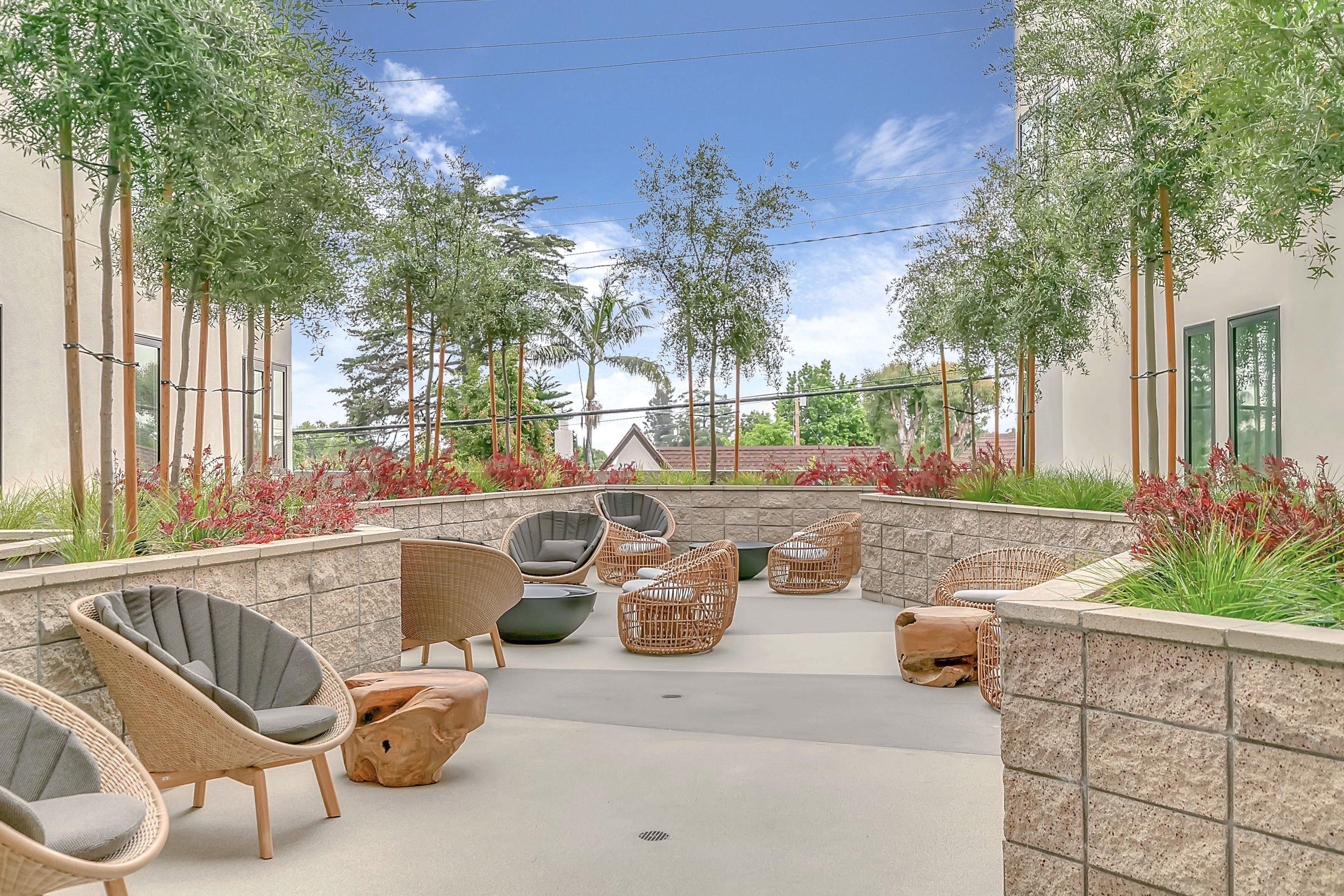 A patio area with wicker furniture and plants at The Rinrose, an apartment community targeting multifamily living.