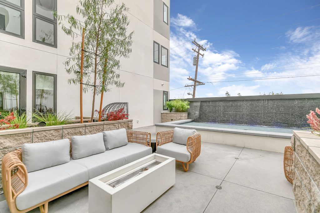 A patio with furniture and a fire pit in front of a Pasadena apartment building.