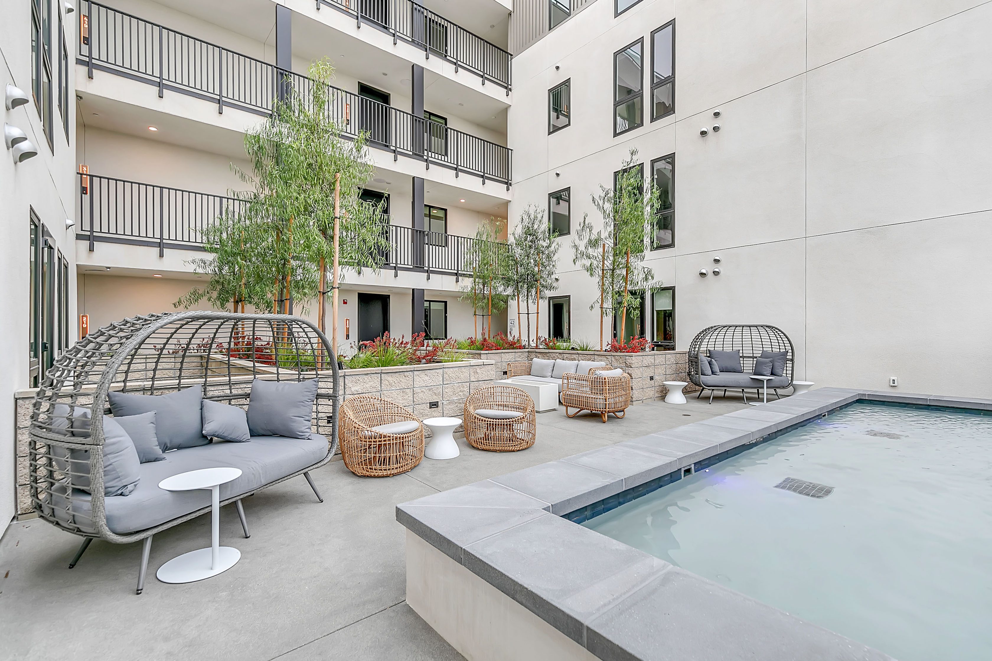 A swimming pool and lounge chairs in the courtyard of The Rinrose, an apartment building in Pasadena.