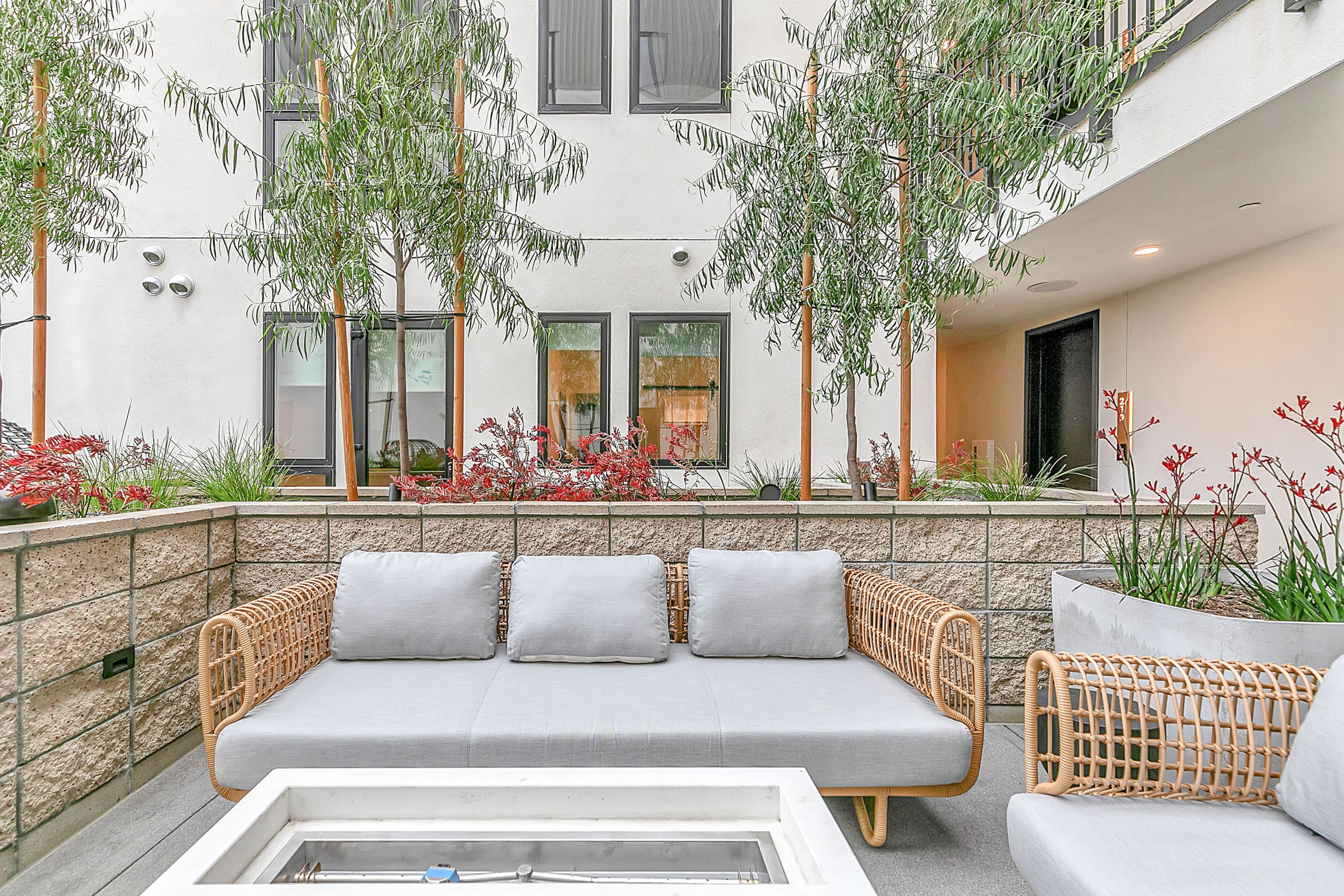 A multifamily patio with wicker furniture and a fire pit at The Rinrose in Pasadena.